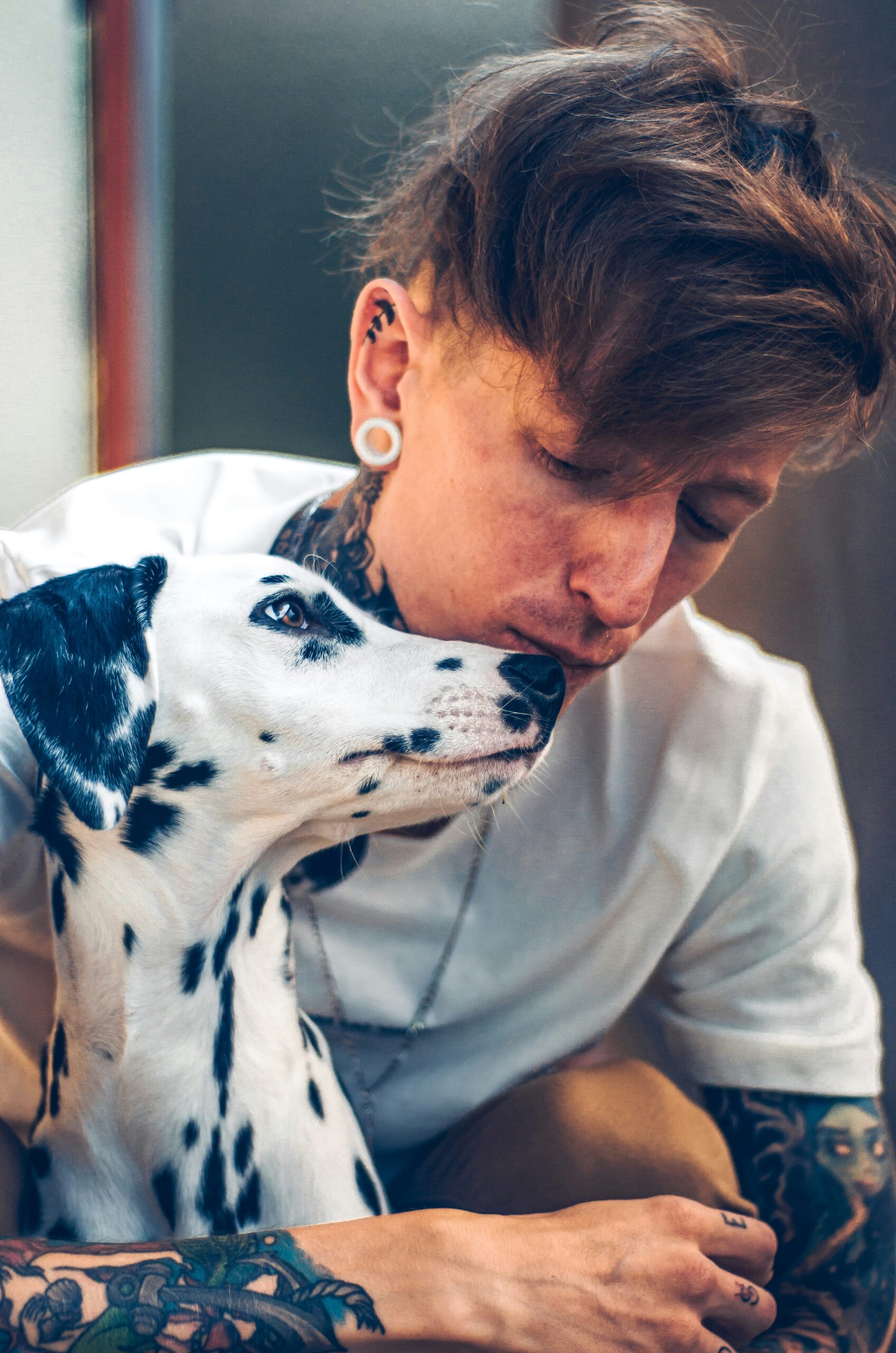 woman in white shirt hugging dalmatian dog